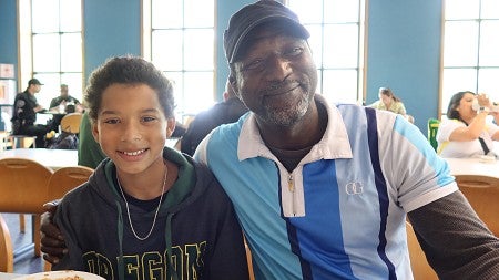 A man and his son smile while at lunch in a cafeteria