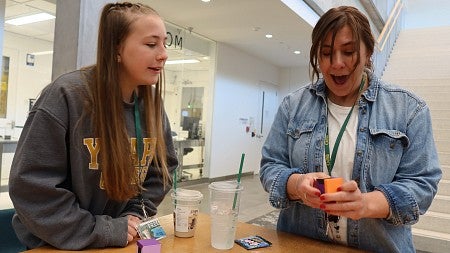 A woman laughs while solving a 3D puzzle as her daughter watches